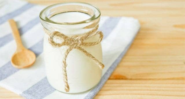 A jar of plain yogurt on wooden table with copy space. Healthy food concept.
